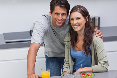 坐在厨房的一对夫妇微笑快乐女性食物男性橙汁女士柜台团结夫妻图片