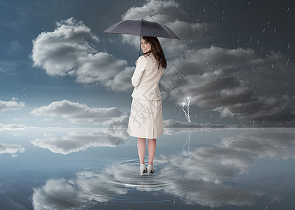 持有黑伞的女商务人士闪电地平线下雨女性太阳蓝色受保护水坑人士天空图片