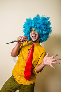 带着蓝假发的疯狂 搞笑的年轻人绿色狂欢幸福领带歌手头发蓝色创造力男人小丑图片