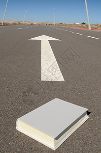 在通向未来的沥青街上的书和箭图片