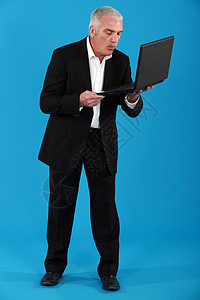 持有便携式计算机的灰色头发商业商图片
