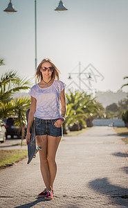 在户外带滑板的年轻女孩闲暇溜冰者城市青年街道棕榈青少年黑发滑冰美丽图片