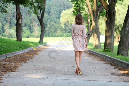美丽的年轻女子在夏日公园走来走去人行道女士女孩金发女郎女性粉色裙子冒充成人屁股图片