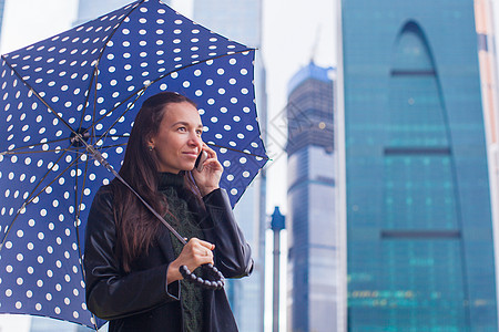 年轻有魅力的女商业青年在雨天用伞下通过电话交谈图片