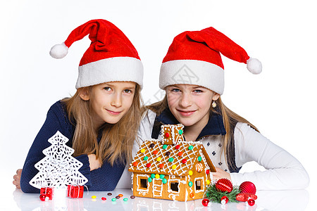 在圣诞老人帽子的女孩 与姜饼屋假期女性微笑蛋糕庆典乐趣食物孩子幸福房子图片