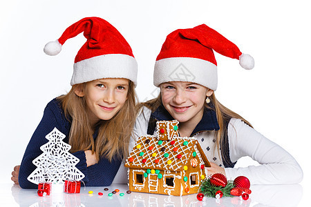在圣诞老人帽子的女孩 与姜饼屋房子乐趣女性蛋糕幸福微笑传统食物庆典假期图片