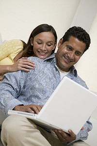一对夫妇在客厅沙发上一起使用笔记本电脑图片