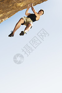 男性登山者从悬崖上跳到晴空的低角度视图图片