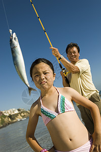 女孩对父亲在海滩钓鱼不满意图片