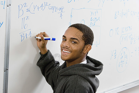 在教室的白板上解决代数方程式时微笑的男生学生平面图片