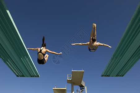 看见两名妇女从潜水板上跳水 向清蓝的天空俯冲图片