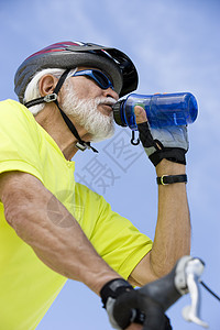 高龄男性骑自行车的饮用水在天空中的低角度视图图片