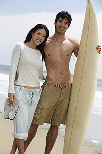 快乐情侣的肖像 海滩上有冲浪板图片