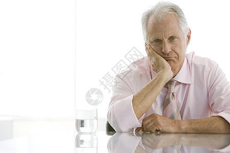 坐在办公桌前手对面的疲劳老年商务人士的肖像图片