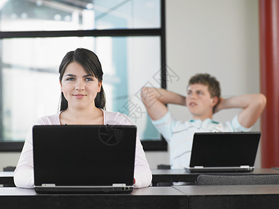 年轻女性看不起笔记本电脑和背景男子图片
