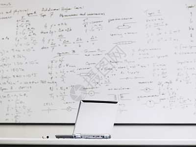 教室桌上的笔记本电脑 背景是白板图片
