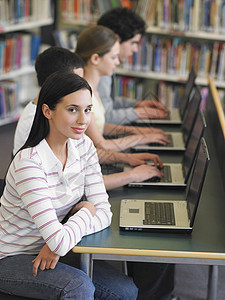 利用图书馆的笔记本电脑 对十几岁女孩和朋友排成一排的少女画像男生沟通种族桌子友谊知识班级学习青少年技术图片