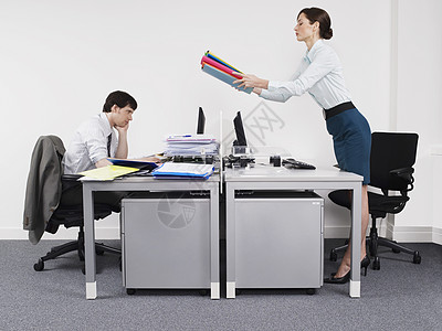 商业女商务人士的侧面视图 将文件夹通过办公桌传送给男同事图片