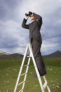 在山区通过双望远镜看望山地的阶梯上一整群商务人士步梯逆境经理梯子商业男人农村男性多云搜索图片