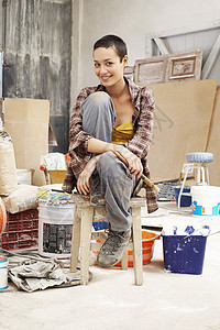 坐在工作场所凳子上年轻女画家的肖像图片