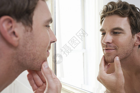 一名年轻人在镜子中检查他的小碎片背景图片