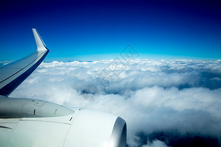 空中机翼在蓝色天空中飞过飘浮的云层上空飞行图片