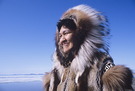 穿着传统服装的爱斯基摩微笑女性在风中与清蓝天空对抗图片