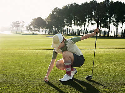 全年年轻女性高尔夫球手 将球投在踢球上图片