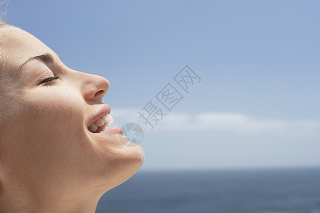 在海滩上闭着眼睛的美女的侧面景色图片