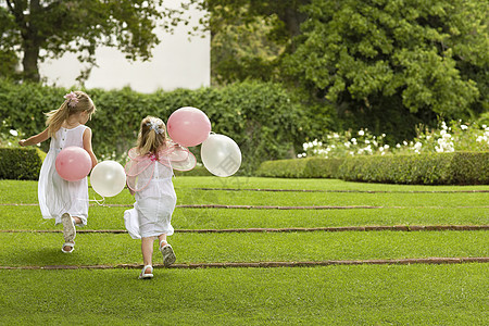 在花园里流着气球的小伴娘的近视草地婚姻女孩跑步童年婚礼兄弟孩子们孩子团结图片