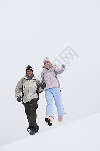 几人从雪覆盖的山丘低角视图下跑下来喜悦女士休闲服装跑步丘陵俏皮女性团结男人图片