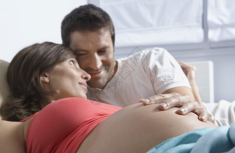 男人在家中睡觉时触摸孕妇胃部说谎肚子女士腹部亲密感怀孕身份家庭夫妻孕妇装图片