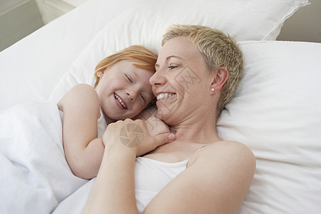 幸福的母亲和女儿一起躺在家中的床上 生活愉快图片