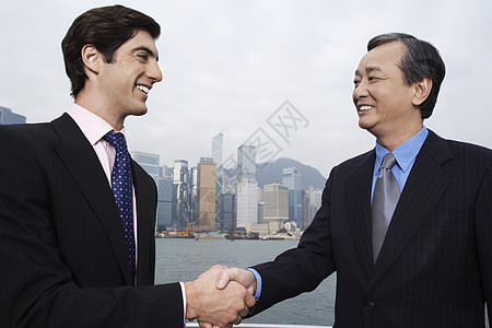 两个商务人士在背景中握握手的男子办公大楼;图片