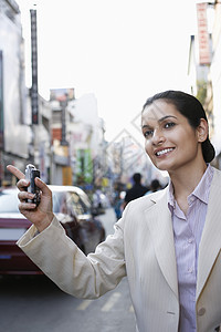 美丽的年轻女商务人士 手机在市街的出租车上欢呼计程车图片