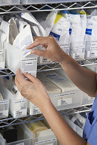 女药剂师在有医疗用品的货架上的手图片