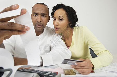 一对非裔美国忧心的情侣在家用信用卡看开销收据时图片