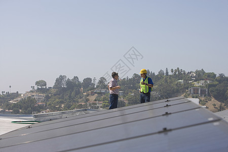 维修工人站在加州洛杉矶屋顶的太阳能电池阵列上 并站立在一起男性太阳能板成年成人发电天空能源燃料环境问题光伏图片