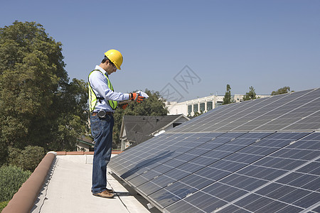 维修工人与在洛杉矶屋顶的太阳能电池阵列站在一起 并站在加利福尼亚州屋顶上图片