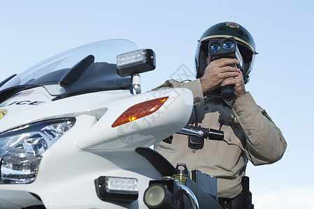 巡逻军官坐在摩托车上 通过超速计看车制服执法头盔物体衬衫交警法律车辆秩序绿色图片