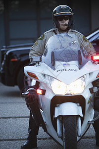 巡逻军官坐在摩托车上 灯光亮着太阳镜秩序绿色法律成人警察头灯车辆对讲机眼镜图片