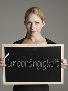 年轻商业女商务人士身着黑板 德语文本为“”(独立主义)的肖像图片