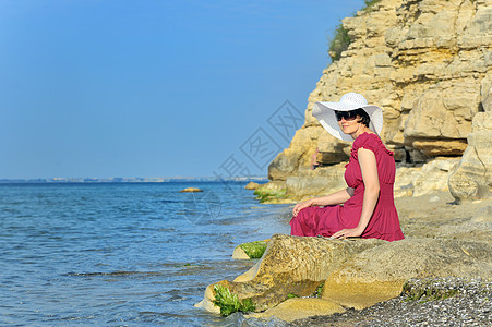 年轻女子在海滩上的肖像女孩化妆品帽子女士广告姿势天空快乐岩石女性图片