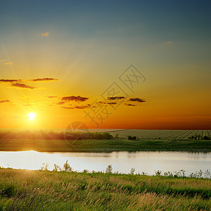 河上绿边的橙色日落背景图片