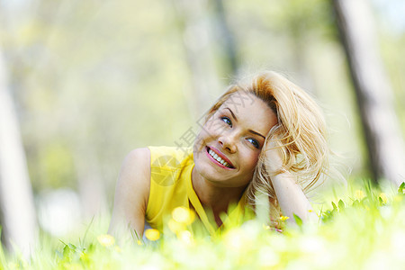 女人躺在草地上快乐幸福金发绿色公园晴天女孩黄色微笑闲暇图片