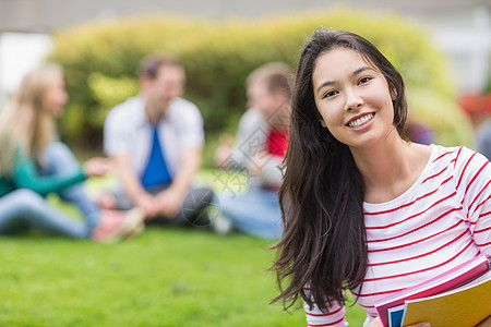 带着模糊的朋友在公园里微笑着笑着的大学生男人学校女性长发棕色图书头发大学沟通互动图片