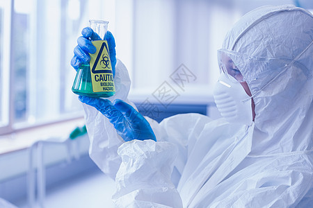 实验室酒瓶中有害化学品防护服和危险化学剂的科学家图片