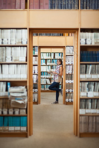 一个微笑着的女学生在图书馆里站满身笑容图片
