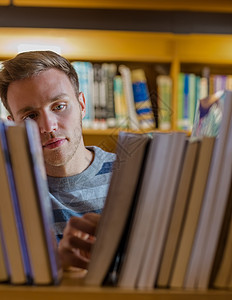 男学生在图书馆中选择书本书架读者文学智力男人阅读家庭架子教科书知识图片