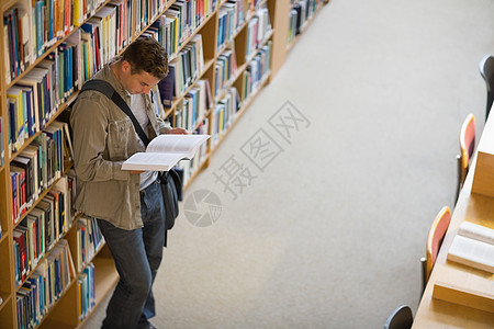 学生阅读图书馆藏书架上的书本背景图片